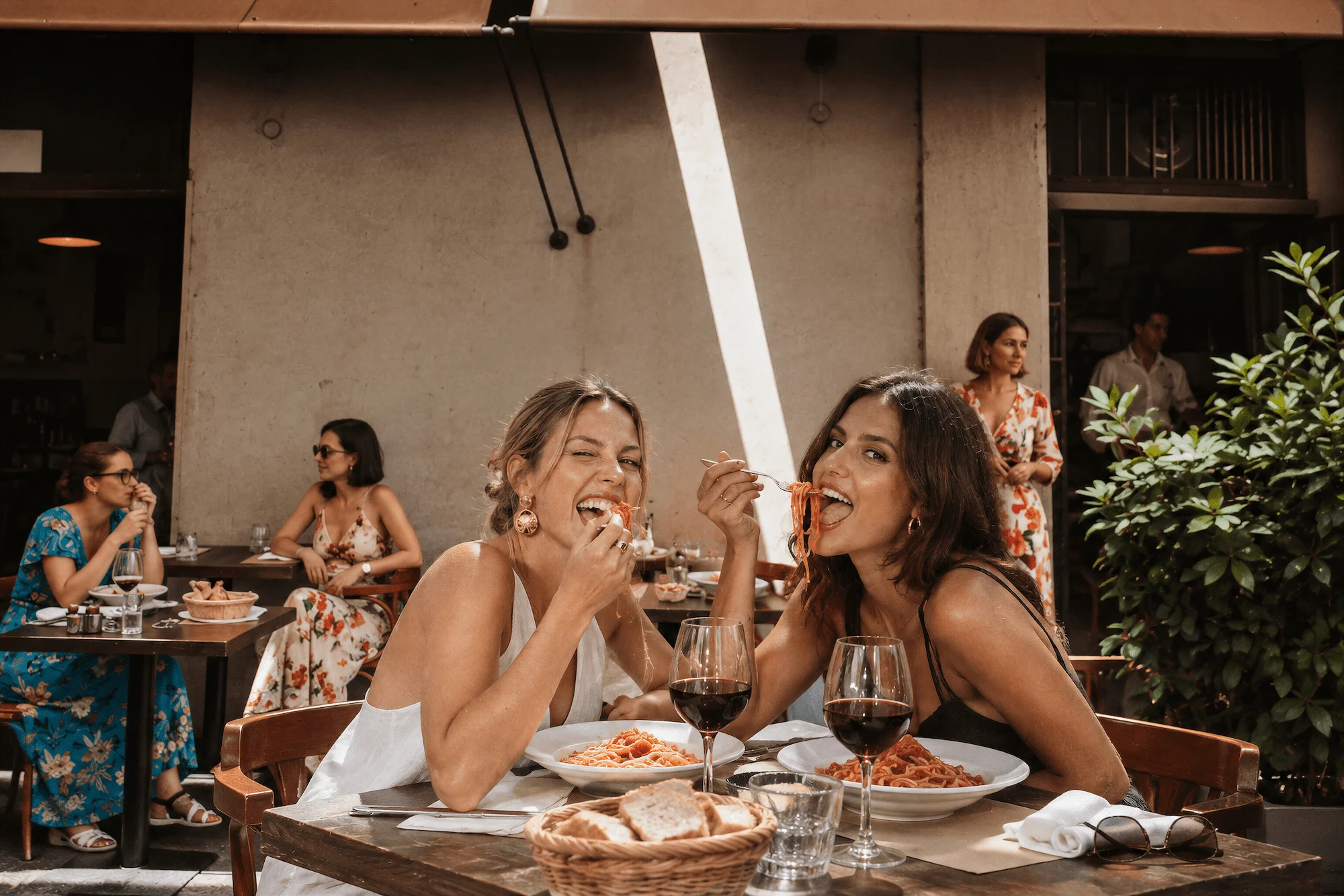 Due ospiti assaggiano la pasta ai tavoli all’aperto