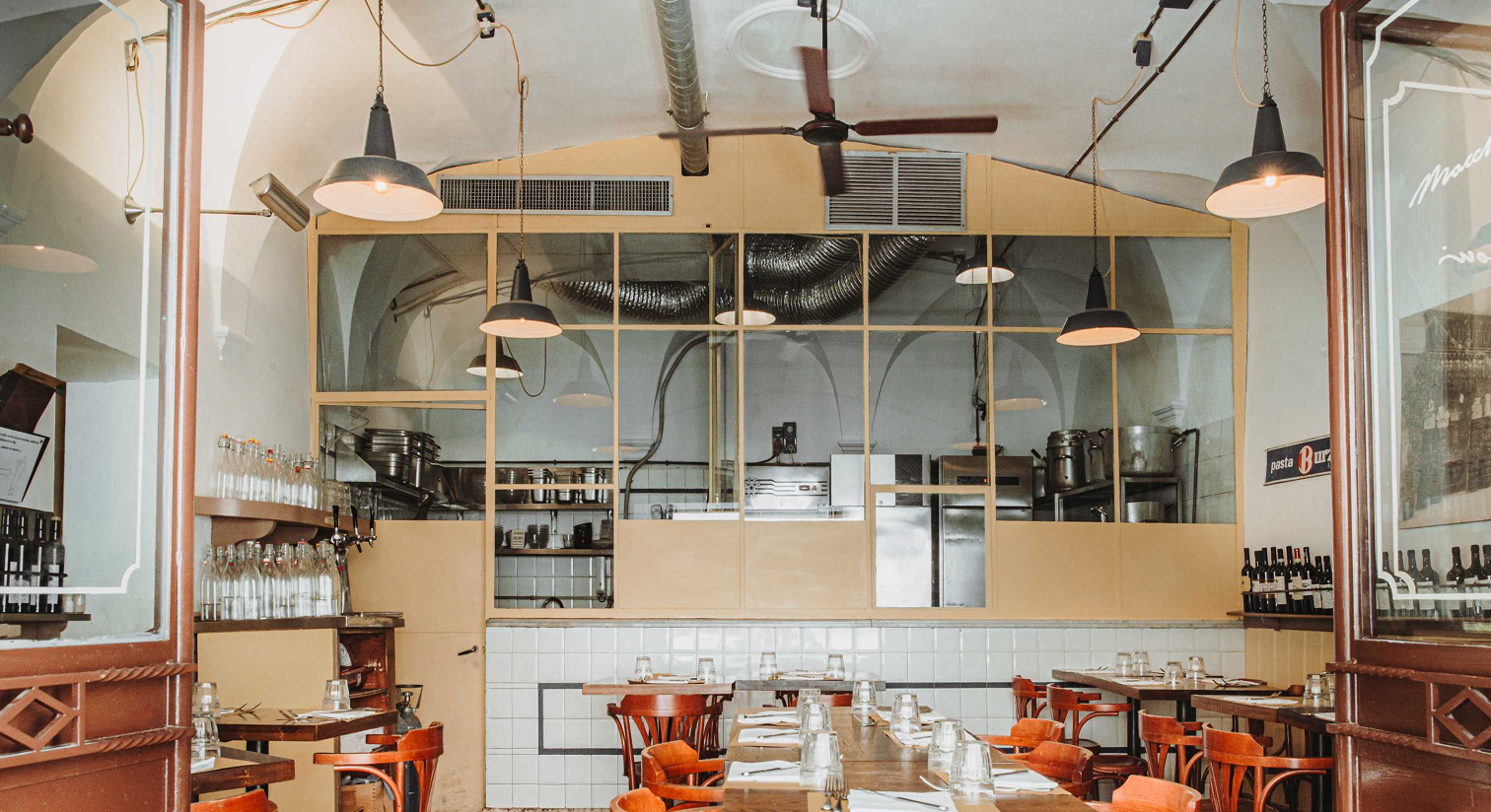 La cucina a vista del ristorante Maccheroni, con vetrate e lampade sospese